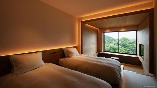 two beds in a room with a window at くろしお想 in Shirahama