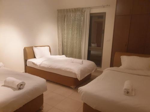 a hotel room with two beds and a window at Flat Luxury 2 bed rooms apartment talabay aqaba in Aqaba