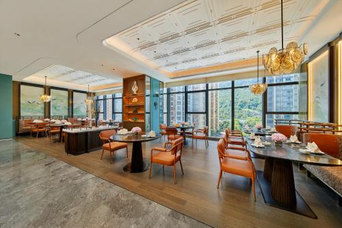 uma sala de jantar com mesas, cadeiras e janelas em Doubletree By Hilton Ya'An em Ya'an