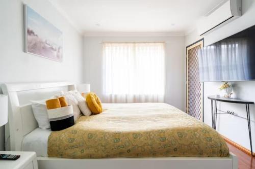 een witte slaapkamer met een groot bed met gele kussens bij Culture Paradise 3BR 2 story Townhouse Cabramatta in Cabramatta