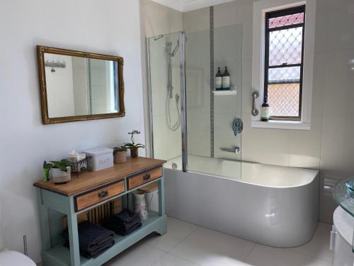 a bathroom with a tub and a shower and a sink at Pomona Noosa Hinterland Homestay in Pomona
