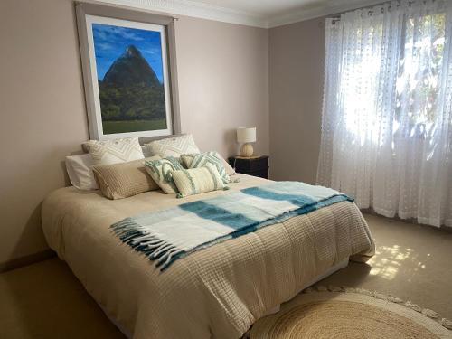 a bedroom with a bed with a blanket and a window at Pomona Noosa Hinterland Homestay in Pomona
