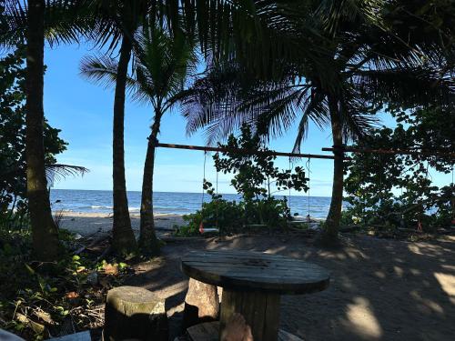 a wooden table on a beach with palm trees at Caribbean View in Tortuguero