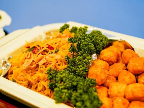 a plate of food with broccoli and noodles at Hotel AreaOne Sakaiminato Marina in Sakaiminato