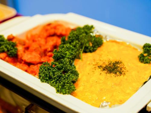 a plate of food with broccoli and sauce at Hotel AreaOne Sakaiminato Marina in Sakaiminato