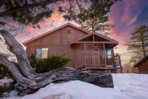 a log in front of a house in the snow at Villa Grove by Rather Be Properties in Big Bear Lake