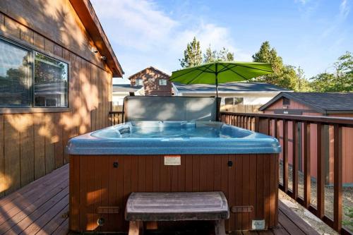 a hot tub on a deck with an umbrella at Villa Grove by Rather Be Properties in Big Bear Lake