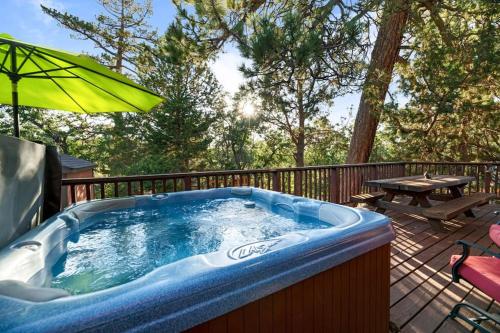 a hot tub on a deck with an umbrella at Rather Be Mountain Getaway in Big Bear Lake