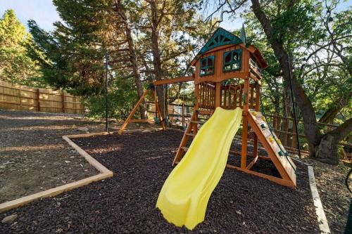 a playground with a yellow slide and a house at Villa Grove by Rather Be Properties in Big Bear Lake