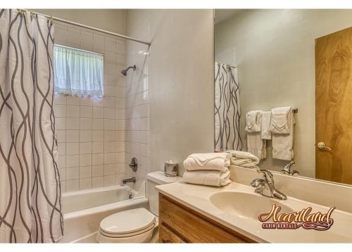 a bathroom with a sink and a toilet and a tub at Honeymoon Cabin with Great Mountain View and Hot Tub in Gatlinburg