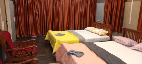 1 Schlafzimmer mit 3 Betten und roten Vorhängen in der Unterkunft Alleppey Beach La Casa in Alappuzha