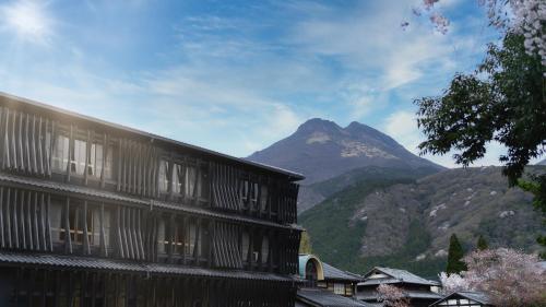 a building with a mountain in the background at Enokiya Ryokan in Yufuin