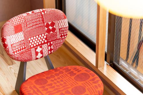 a red chair sitting next to a window at Enokiya Ryokan in Yufuin