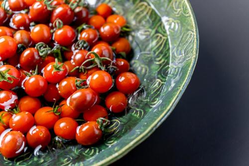 a green glass bowl filled with tomatoes on a table at Enokiya Ryokan in Yufuin