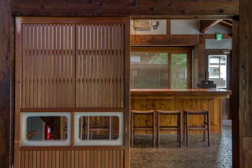 a room with a bar and some chairs in a building at Enokiya Ryokan in Yufuin