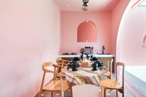 una sala da pranzo con tavolo, sedie e pareti rosa di VA Villa Jimbaran Bali a Jimbaran