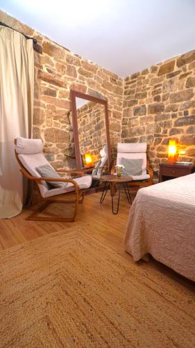 a bedroom with a stone wall and two chairs and a mirror at Posada Venta Hornizo in Arenas de Iguña