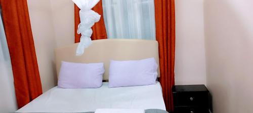 a bed with two purple pillows in front of a mirror at Comfort Inn in Kisumu