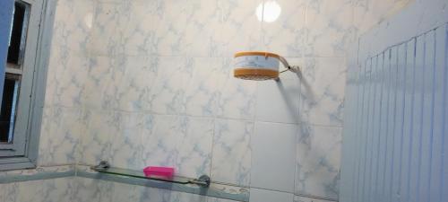 une salle de bains carrelée de blanc avec un distributeur de savon sur le mur dans l'établissement Comfort Inn, à Kisumu