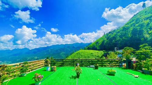 a view of a green field with mountains in the background at Hà Lù Homestay in Lao Cai