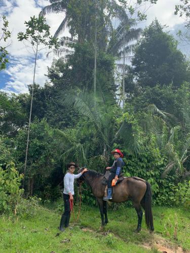 un hombre está de pie junto a un niño en un caballo en Finca El Tesoro, en Carmen de Apicalá