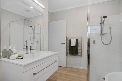 a white bathroom with a shower and a sink at Another on Leo in Waihi Beach