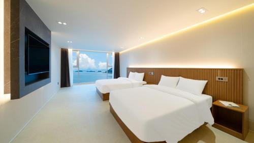 a hotel room with two beds and a large window at Stone Island Pool Villa in Yeosu