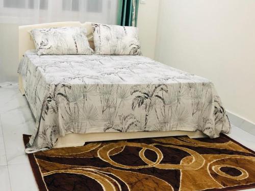 1 cama con manta y almohadas encima de una alfombra en villa piscine orchidée, en Pointe-Noire