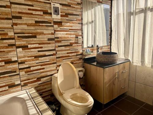 a bathroom with a toilet and a wooden wall at Hotel Esmeralda in La Paz