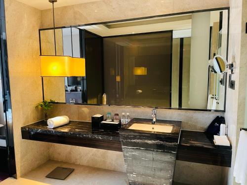 a bathroom with a sink and a large mirror at Maanshan Wanda Realm Hotel in Dangtu