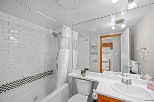 a bathroom with a sink and a toilet and a tub at Alpenglow Lodge Cozy Studio with Den by MVA in Whistler