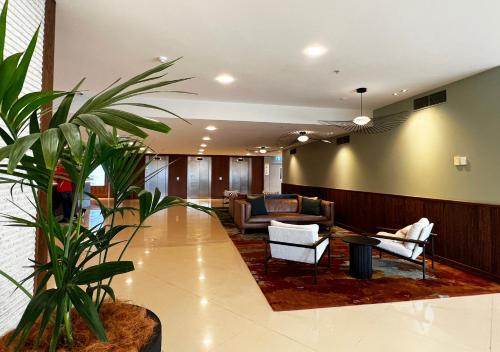 a lobby with a couch and a chair and a plant at Sudima Auckland Airport in Auckland