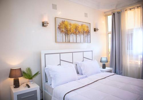 布拉薩維爾的住宿－residence queen house，卧室配有白色的床和墙上的绘画作品