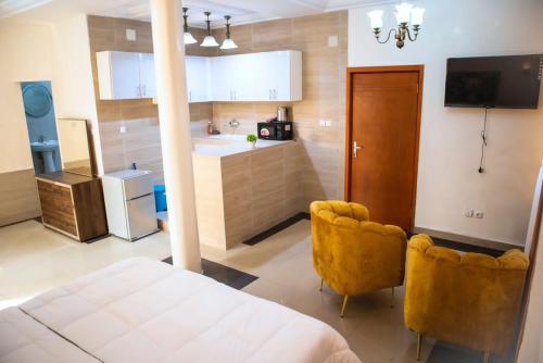 uma cozinha com uma cama e duas cadeiras num quarto em residence queen house em Brazavile