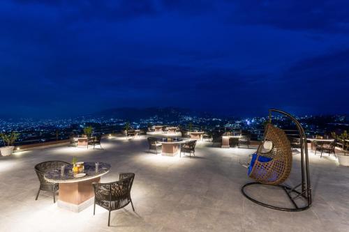 a rooftop patio with tables and chairs at night at Sky Garden Resort in Dhulikhel