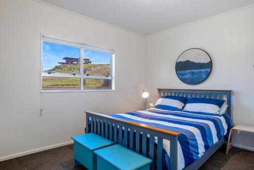a bedroom with a blue and white bed and a window at Beachfront Favourite - Foxton Beach Holiday Home in Foxton Beach