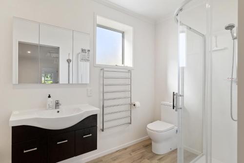 a bathroom with a sink and a toilet and a shower at Beachfront Favourite - Foxton Beach Holiday Home in Foxton Beach