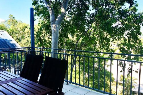 a wooden bench sitting on a balcony next to a tree at Salt & Sand - Tropical Oasis Footsteps to Beach in Trinity Beach
