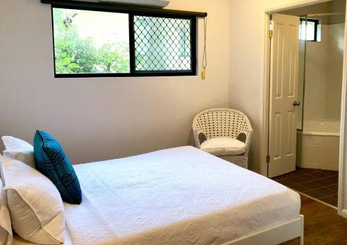 a bedroom with a bed and a window and a chair at Salt & Sand - Tropical Oasis Footsteps to Beach in Trinity Beach