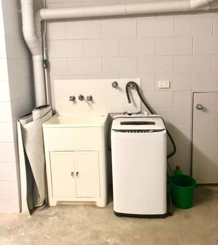 a bathroom with a sink and a washing machine at Salt & Sand - Tropical Oasis Footsteps to Beach in Trinity Beach