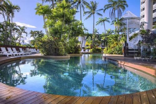 a swimming pool in a resort with chairs and palm trees at 'Luxury Waterfront' Spectacular Oasis in the City in Cairns