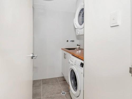 a white laundry room with a washer and dryer at 'Luxury Waterfront' Spectacular Oasis in the City in Cairns
