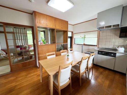 eine Küche mit einem Holztisch und Stühlen in der Unterkunft シークレットベースゆふいん in Yufu