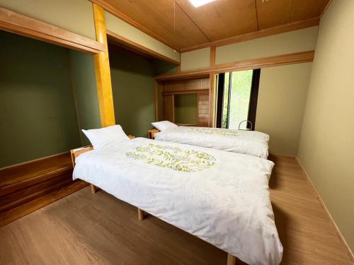 2 Betten in einem Zimmer mit Fenster in der Unterkunft シークレットベースゆふいん in Yufu