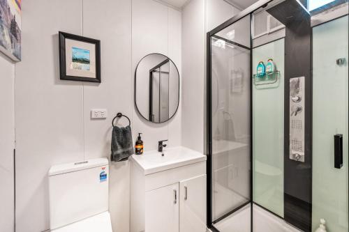 a bathroom with a shower and a sink and a mirror at Delightful Container House with Views in Hartley