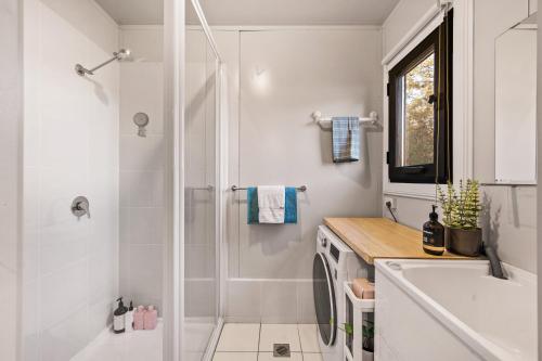 Un baño blanco con ducha y lavabo. en Delightful Container House with Views, en Hartley