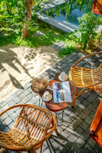 a patio with two chairs and a table with a book at Faifo Retreat Villa Hội An in An Bang