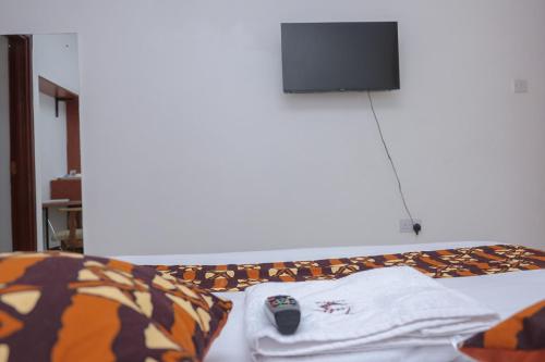 VIJIJI HOTEL & CONFERENCE في إلدوريت: سرير مع تي شيرت وريموت كنترول عليه
