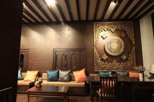 a living room with a couch and tables and a wall at Baan Ratchiangsaen in Chiang Mai
