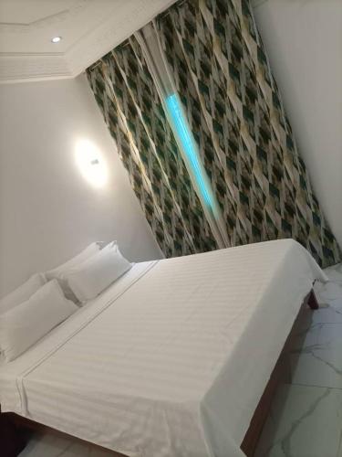 a white bed in a room with a wall at appartement 2 crepin in Pointe-Noire